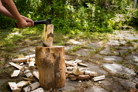 young man chopping wood with an axe outside on a chopping blockの写真素材