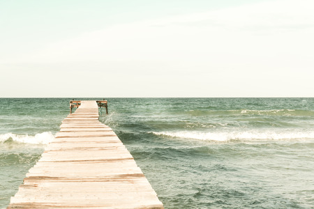 Retro look of a pier in the mediterranean ocean from the beachの写真素材