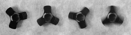 Hand spinner in different motions. A fidget toy for increased focus, stress relief. Gray concrete backgroundの写真素材