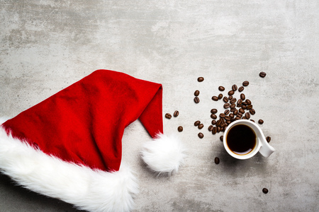 Red santa hat, a cup of coffee and coffee beans on a gray concrete tableの写真素材