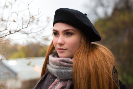 Young woman with brown beret and blue scarf.  She is outside and look into the camera.の写真素材