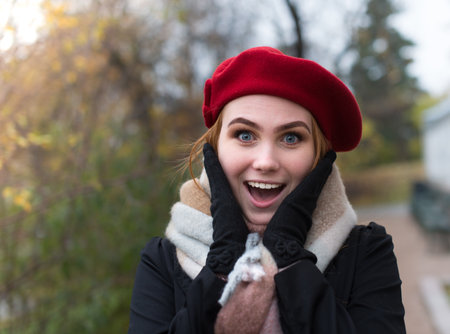 Young woman with brown beret and blue scarf.  She is outside and look into the camera.