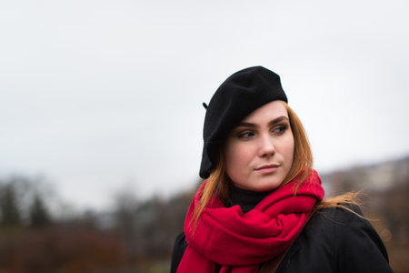 Young woman with brown beret and blue scarf.  She is outside and look into the camera.の写真素材