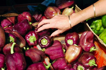 Woman reaching for a purple bell pepper in a bin at the Farmers Marketの写真素材