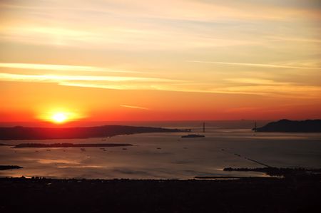 Sun setting over the San Francisco Bay and Golden Gate Bridgeの写真素材