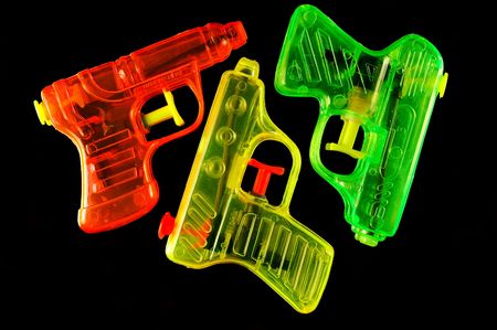 Three toy squirt guns isolated on a black mirrored backgroundの写真素材