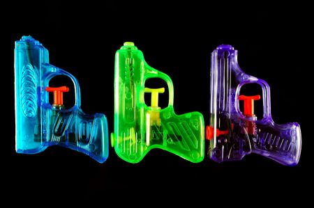 Three toy squirt guns isolated on a black mirrored backgroundの写真素材