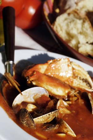 Traditional San Francisco meal of a bowl of cioppino, artichokes and fresh sourdough bread set outdoors on a vintage tablecloth.  Cioppino was created in the early 1900's by fisherman on the wharfs of San Francisco, California, who "chipped in" their dailの写真素材
