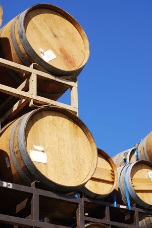 Wine barrels stacked high against a clear blue sky