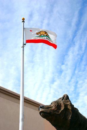 Bronze statue of a bear looking skyward at the California State flag with the Golden State Bearの写真素材