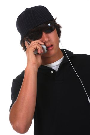 Thirteen year old Asian-Caucasian boy talking on cellphone and listening to mp3 playerの写真素材