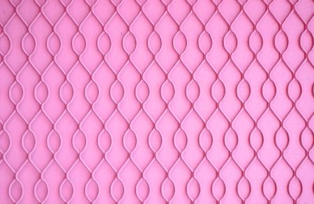Wire mesh on a wall painted bright pinkの写真素材