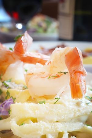 Shrimp atop a plate of Fettuccini Alfredo in restaurantの写真素材