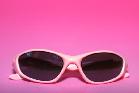 Pair of pink women's sports sunglasses on a pink background の写真素材
