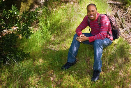 African American college student sitting on a grassy hillsideの写真素材