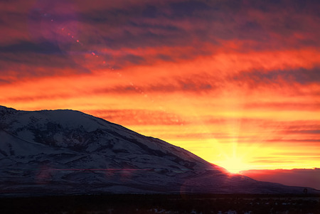 Sun setting behind snowy mountain near Winnemucca, Nevadaの写真素材