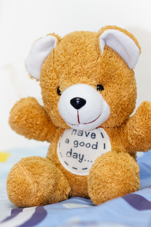 brown bear doll sit on bed in bedroomの写真素材