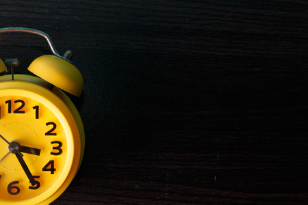 yellow retro alarm clock on wood background photo