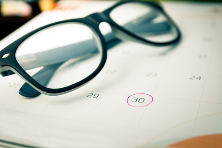 close up calender and marking with pink circle and eyeglasses, very soft focus and vintage toneの写真素材