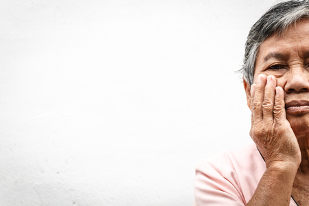 close up asian old woman hiding face with her handsの写真素材