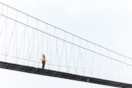 beauty asian woman in yellow wear and black jeans and wool hat on the wooden bridgeの写真素材