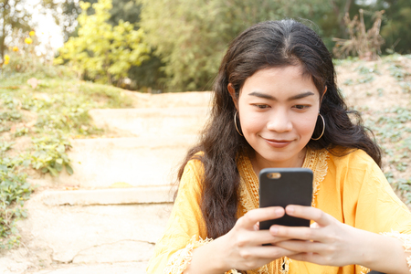Beauty asian woman in yellow wear and black jeans sitting and use smartphoneの写真素材