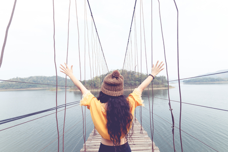 beauty asian woman in yellow wear and black jeans and wool hat on the wooden bridgeの写真素材