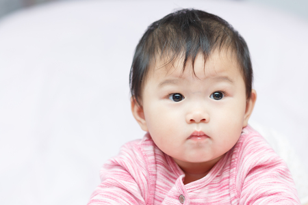 close up asian adorable baby, new born children toddler on soft textile bedの写真素材