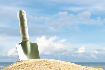 close up green shovel at sand of beach on blur beautiful summer sky backgroundの写真素材