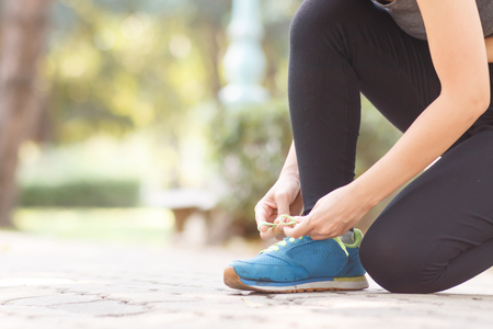 close up of woman tying shoe runner preparation to exersice on parkの写真素材