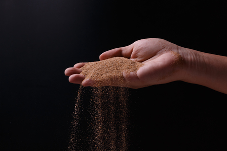 sand explosion with right hand on black backgroundの写真素材