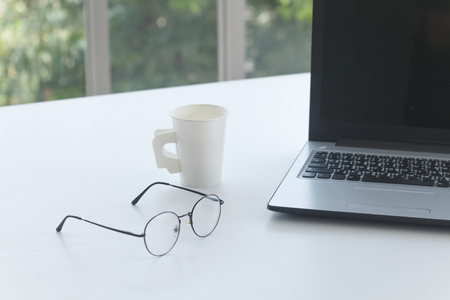 laptop and glasses on white working tableの写真素材