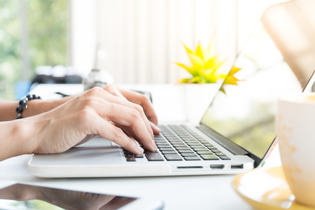 worker typing on laptop on desk near window in cafeの写真素材