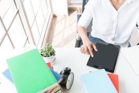 close up asian woman touch smart pad on desktop near window in workplace,の写真素材