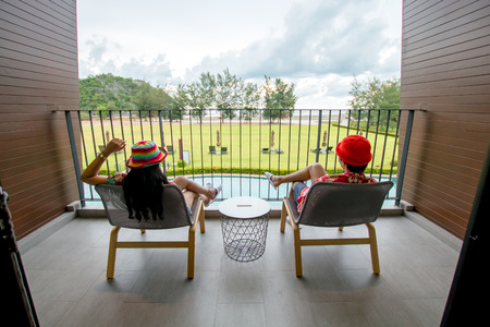 beautiful view looking from bedroom of resort and couple asian people sitting at chair, relaxation in vacation conceptの写真素材