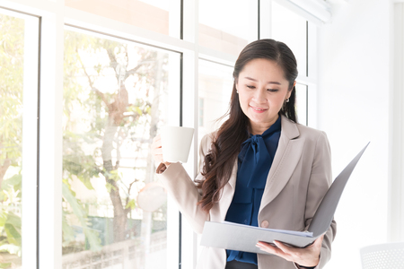 close up beauty asian business woman hoding a cup of coffee near window for relaxation time and happy,successful conceptの写真素材