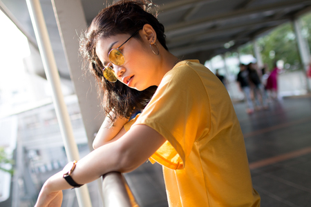 beauty asian woman with yellow wear and glasses in cityの写真素材