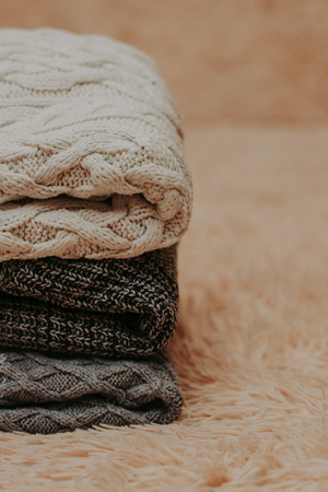 knitted sweaters on a soft peach carpet close-up, place for text - Image