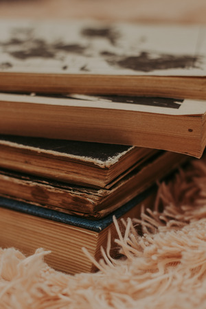 A stack of old books on a cozy fluffy beige blanket. Place for text. Close-upの写真素材