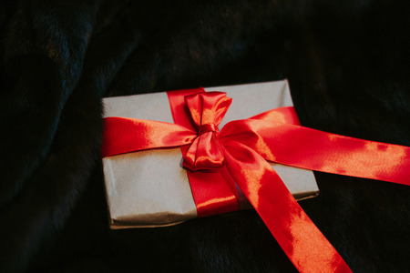 Kraft paper envelope tied with a red ribbon as a gift message. The gift is tied with a red bow against the background of beautiful natural fur. Top View - Imageの写真素材