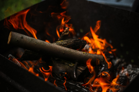 Red flame from a cut of a tree, dark gray coals inside a metal brazier. Firewood burning in a brazier on a bright yellow flame. Flames of fire preparing for cooking kebabs. Charcoal brazier coalの写真素材