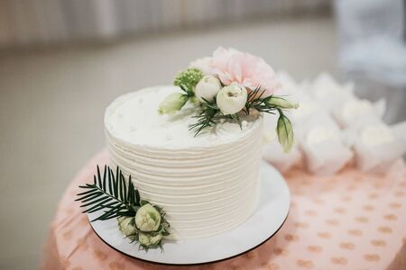 White wedding cake with flowers and blueberries on the table