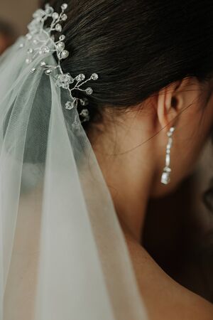 Wedding earrings on a female hand, she takes the earrings, the bride fees, morning bride, white dress, wear earringsの写真素材