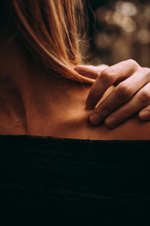 The girl holds her hand on her shoulder. Back view. Woman's head and shoulder. Hand of a young woman. Medical osteoporosis conceptの写真素材