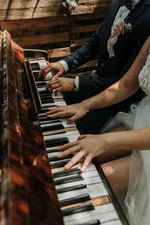 The bride and groom play the piano in two hands. Hands of the newlyweds on the piano keys.の写真素材