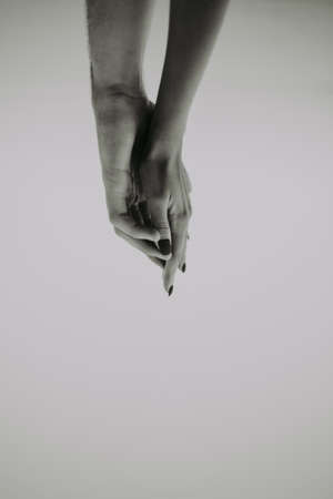 intertwined hands of a man and a woman on a gray background, the concept of love and tendernessの写真素材