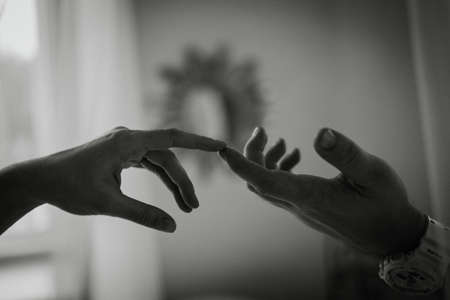 Hands of man and woman on the background of the window. The gentle touch of a man and a woman. Love connection help concepts. Be hand in hand. Touching each other. Black and whiteの写真素材