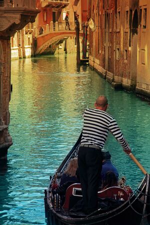 Venice gondolier rides tourists through the canals of Venice.の写真素材
