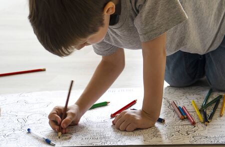 boy paints a large coloring book on the floorの写真素材