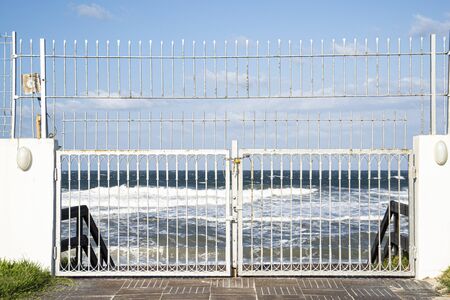 White closed gates to the beach due to large waves. Mahdia, Tunisia.の写真素材